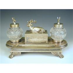 A Victorian silver plated desk stand, with 2 globular cut glass inkwells, a seated stag and 2...