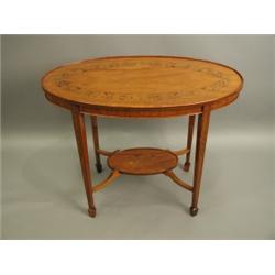 An Edwardian satinwood veneered oval table, the top and lower shelf inlaid with leaf and ribbo...