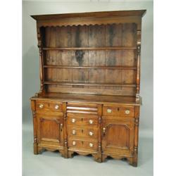 An early 19th Century Welsh dresser in oak, walnut & mahogany, the closed plate rack with a wa...