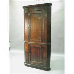 A George III oak free standing corner cupboard, each panelled door opening to reveal traces of...