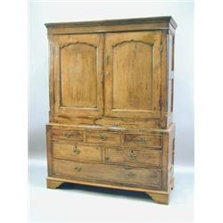 An early 18th Century oak wardrobe, with shaped and moulded panelled doors flanked by reeded p...