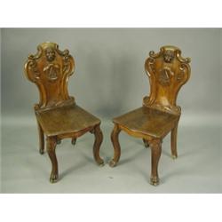 A pair of Victorian oak hall chairs the cartouche shaped back carved each with a lions head, c...