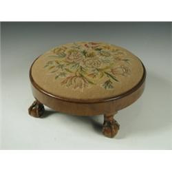 A 1930s walnut footstool with a circular embroidered seat on claw and ball feet Est. 100/150...