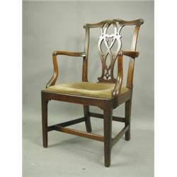 An 18th Century mahogany elbow chair, with a carved and pierced splat, scroll 'ears' and a dro...