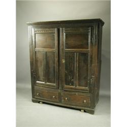 An 18th Century oak wardrobe with a carved frame, and plain panelled doors, over two bottom drawe...