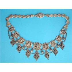 An Indian silver necklace designed as a row of 9 graduated pierce work oval sections depicting de...