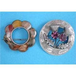 A Scottish pebble brooch and a silver thistle brooch set amethyst colour pastes....