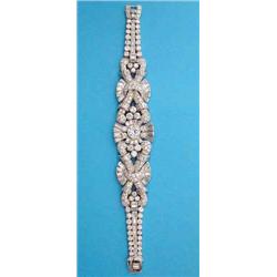 An important 1950's diamond and platinum bracelet of scroll design, the centre panel collet set w...