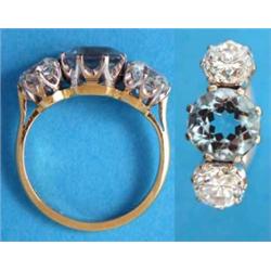 An 18ct. gold 3-stone aquamarine and diamond ring claw set with a round cut aquamarine flanked by...