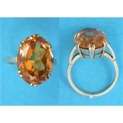 A gold dress ring claw set with an oval cut synthetic yellow sapphire....