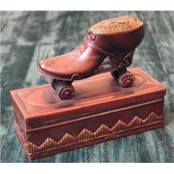 An unusual early 20th century patinated brass pin cushion box in the form of an early roller-ska...