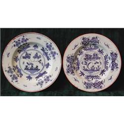 A pair of near matching English Delft plates blue painted with stylised flowers within an orange...