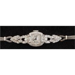 An Art Deco cocktail watch with diamond set bezel and shoulder panels, watch stamped PLATINUM, on...