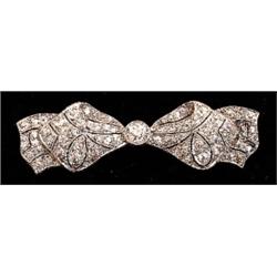 An Art Deco design brooch in the form of a bow, set with brilliant and eight cut diamonds, total...