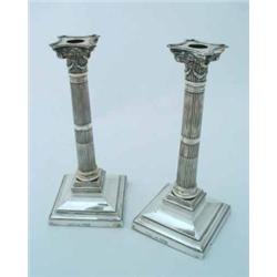 A pair of silver candlesticks, the square-shaped sloping bases with beaded bands, supporting reed...