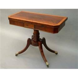 A Regency mahogany card table, the folding top cross-banded in maple with canted angles, on ring-...
