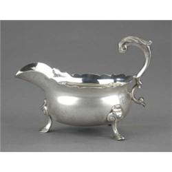 A George II sauceboat, with wavy rim, acanthus capped flying double scroll handle, on three scrol...