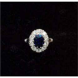 An 18ct white gold, sapphire and diamond cluster ring, the central claw set oval cut sapphire wit...