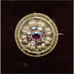 A circular foiled garnet and chrysolite brooch, c.1850, the central circular cut garnet within a...