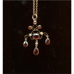 A garnet and pearl pendant, c.1890, of scroll design interspersed with graduated circular cut gar...