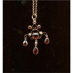 A garnet and pearl pendant, c.1890, of scroll design interspersed with graduated circular cut gar...