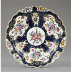 A Worcester blue scale deep plate, the 'mirror' reserves painted with flower sprays within gilt s...