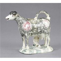 An Allerton cow creamer and cover, standing foursquare, with pink markings and sponged in black,...