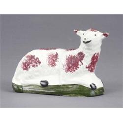 A creamware figure of a resting sheep, sponged in brown and on a green base, 5.5in wide, early 19...