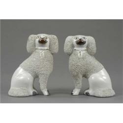 A small pair of Staffordshire figures of seated poodles, with trimmed granulated white coats and...