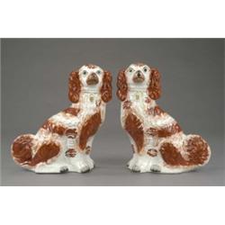 A pair of Staffordshire figures of seated spaniels, with brown splashed coats and bushy tails, bl...