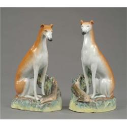 An unusual and well modelled pair of seated greyhounds, with shaded tan coats and well defined mu...