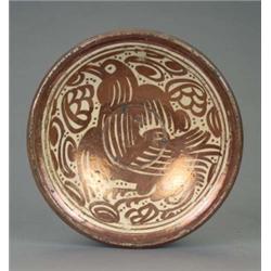 A red lustre Hispano Moresque circular dish, boldly decorated overall with a bird with spread win...