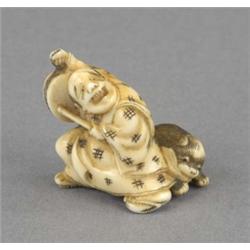 A Japanese ivory netsuke, carved as a laughing figure beating a drum, a playful pup at his feet,...