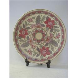 A CROWN DUCAL CIRCULAR PLAQUE, tube-line stylized flowers within a geometric chevron border, pink...