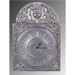 Varia : Wanduhr. Zinn. Rechteckige, oben gebogte ornamentale Platte. Röm. Zahlen, Batteriebetrieb. 2