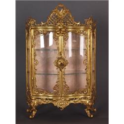 Varia : Sammlungsvitrine. Messing vergoldet. Dreiseitig verglaster, frontal geschweif- ter, zweitüri