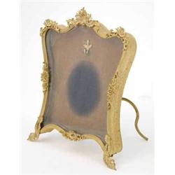 A French gilt brass miniature frame, in the form of an easel with stamped and applied foliate dec...