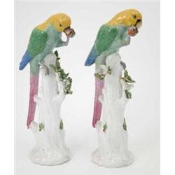 A pair of German porcelain parrot models, perched on tree stumps, (some damage) 12.5ins...