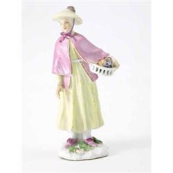 A Meissen miniature figure of a lady holding a basket of flowers, in wide-brimmed yellow hat and...