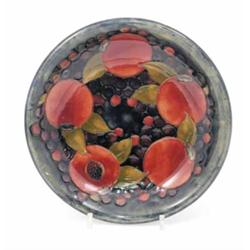 A Moorcroft pomegranate shallow bowl, circa 1925, decorated in shades of blue, orange and ochre,...