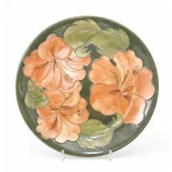 A Walter Moorcroft coral Hibiscus plate, circa 1968-1978, decorated in shades of green and coral...