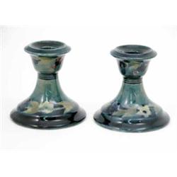 A pair of Moorcroft dwarf candlesticks, circa 1915, decorated with fruit and flowerheads, in shad...