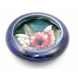 A Moorcroft Orchid dish, circa 1955, decorated in shades of pink, blue, yellow and green against...