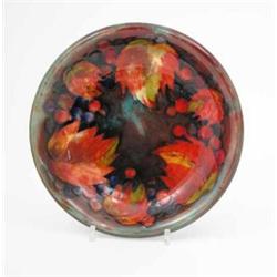 A Moorcroft flambe leaf and berry shallow bowl, circa 1935, decorated in shades of red, blue and...