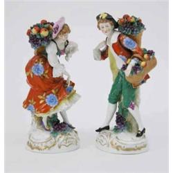 A pair of Samson porcelain figures, male and female fruit-sellers, each holding baskets of apples...