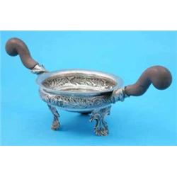 A South American white metal bowl, with wooden scroll handles and foliate scroll feet....