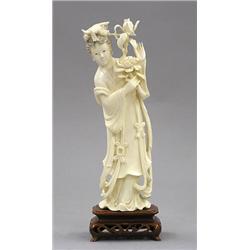 CARVED IVORY FIGURE OF GUANYIN, Chinese. The immortal wearing a long robe tied at the waist hol...