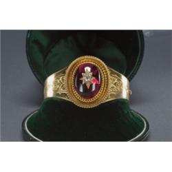 VICTORIAN 18K YELLOW GOLD HINGED BANGLE, with a central medallion set with a large oval garnet ca...