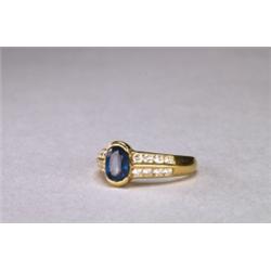 18K YELLOW GOLD RING, set with an oval cut sapphire (approx. 0.90ct.) flanked by 16 channel set b...