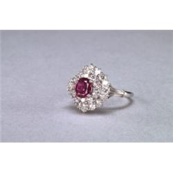 PLATINUM AND 18K WHITE GOLD RING, set with an oval cut ruby (approx. 0.70ct.), encircled by 28...